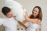 Cheerful couple pillow fighting in bed