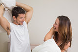 Cheerful couple pillow fighting in bed
