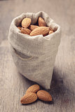 small sack bag full of almonds on wooden table