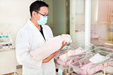 doctor holding a newborn baby in a baby room 