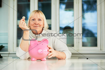 Old woman showing piggybank and euro coin