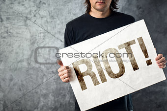 RIOT. Man holding poster with printed protest message