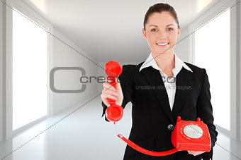 Composite image of charming woman in suit holding a red telephone