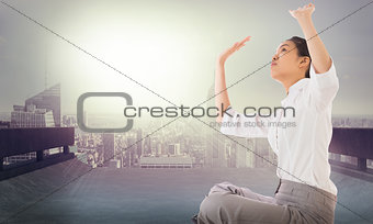 Composite image of businesswoman sitting cross legged pushing up