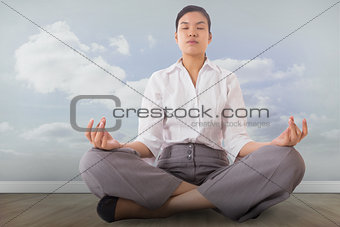 Composite image of businesswoman sitting in lotus pose