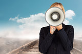 Composite image of closeup of a businesswoman with a megaphone hiding her face