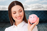 Composite image of confident businesswoman holding a piggybank