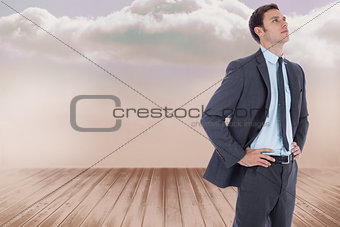 Composite image of serious businessman with hands on hips