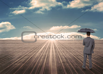 Composite image of rear view of classy businessman holding grey umbrella