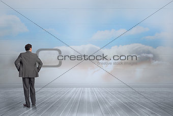 Composite image of businessman with hands on hips