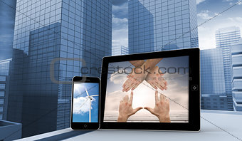 Composite image of hands and wind turbine on smartphone and tablet screens