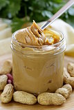 homemade peanut butter with whole nuts on a wooden table