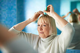 senior woman checking hairline for hair loss
