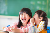 Laughing little girls sharing secrets in class