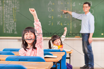 asian pupils raising hands during the lesson 