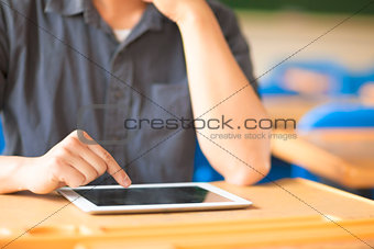 young man using a tablet or ipad in a classroom