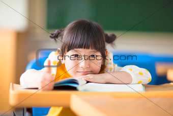 smiling kid lie prone on a desk and thumb up