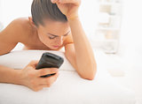 Concerned young woman on massage table with phone