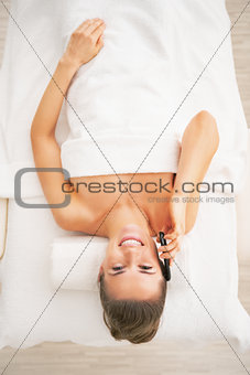 Young woman laying on massage table and talking cell phone