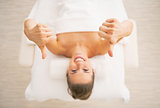 Closeup on smiling young woman laying on massage table and showi