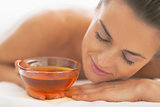 Young woman laying on massage table with honey plate