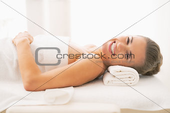 Smiling young woman laying on massage table