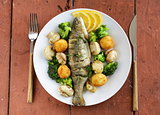 roasted trout fish with vegetables and lemon on a plate