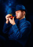 Man with Hat Lighting His Pipe with a Match