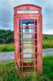 Detail of old red English phone booth in countryside