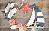 Toy sailboat and fish with seashells and starfish on a wooden ba
