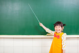 smiling girl using a baton to point on a blackboard