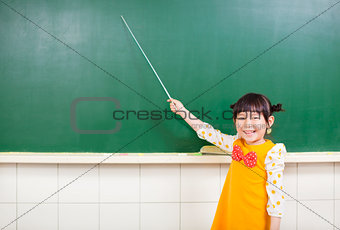 smiling girl using a baton to point on a blackboard