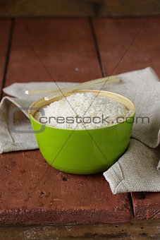 uncooked white rice in a green bamboo bowl