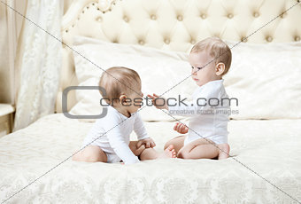 Two baby boys playing on bed at home