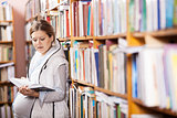 Young pregnant woman reading book in library