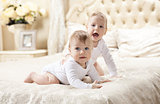 Two baby boys playing on bed at home