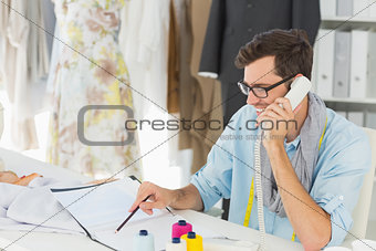 Smiling male fashion designer using phone in the studio