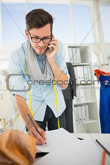 Fashion designer working on his designs while on call