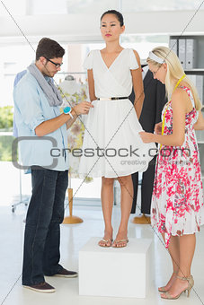 Fashion designers adjusting dress on model