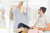 Man with shopping bags while woman selecting a dress