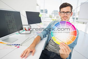 Male artist holding color wheel at desk