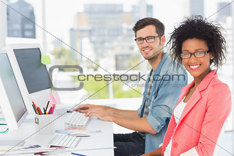 Smiling casual young couple working on computers