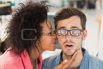 Female artist whispering into colleagues ear