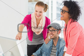 Three cheerful artists working on computer