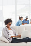 Woman using laptop with colleagues in background at creative office