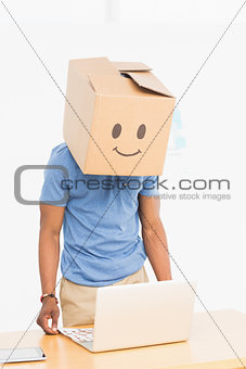 Man with happy smiley box over face in front of laptop