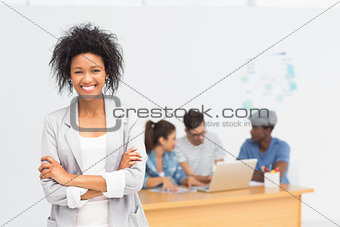 Casual female artist with colleagues in background at office