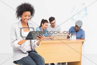 Artist using digital tablet with colleagues in background at office