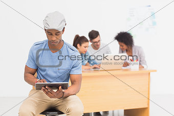 Artist using digital tablet with colleagues in background at office