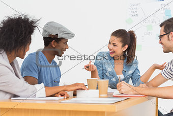 Group of happy artists in discussion at desk